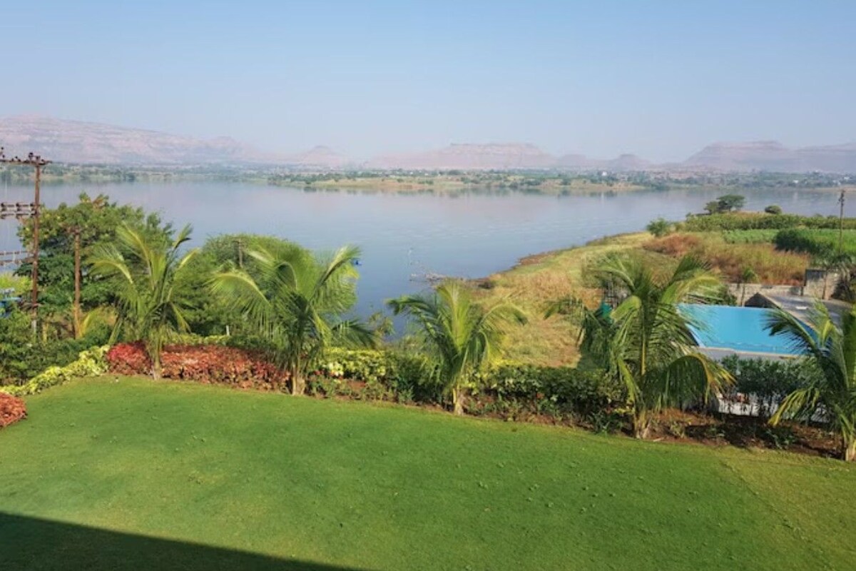 A view of a lake with a grassy area and palm trees in the foreground.