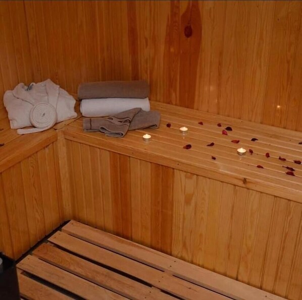 A wooden sauna with benches, towels, and rose petals. - Aydıner Resort Otel (Horasan)