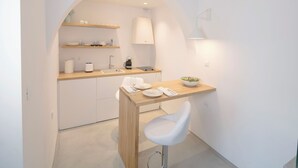 Une cuisine moderne avec des meubles blancs, un plan de travail en bois et un tabouret de bar blanc.