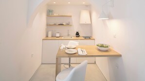 Une cuisine de taille réduite, dotée d’un plan de travail en bois, de meubles blancs et d’une seule chaise.