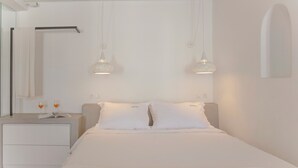 Une chambre à coucher au style minimaliste, avec un lit, des tables de chevet et un luminaire suspendu.