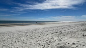 Une vaste plage de sable avec des empreintes et un ciel dégagé.