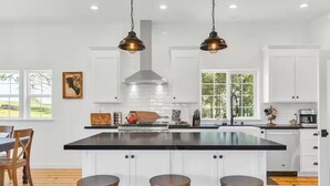 A modern kitchen with a central island, pendant lighting, and white cabinetry.