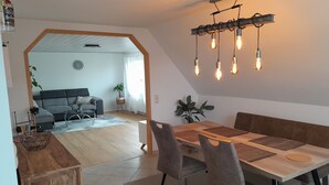 Un comedor moderno con una mesa de madera, sillas tapizadas de gris y una lámpara colgante.