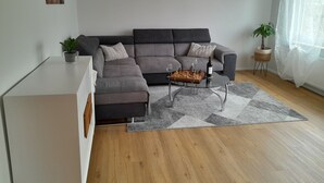 Una sala de estar moderna con un sofá seccional gris, una mesa de centro de vidrio y un tablero de ajedrez.