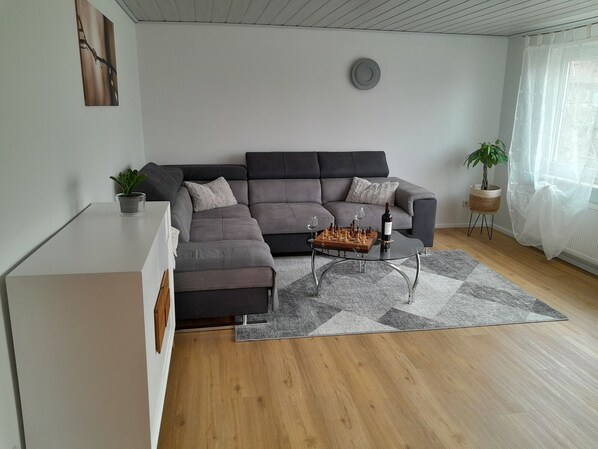 Una sala de estar moderna con un sofá seccional gris, una mesa de centro de vidrio y un tablero de ajedrez.