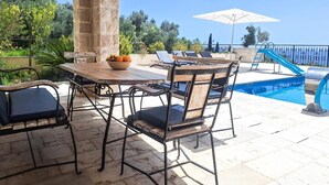 Un patio al aire libre con piscina, columnas de piedra y una mesa con sillas.