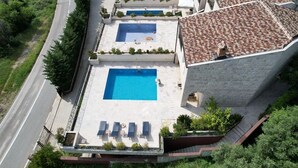 Una piscina en la azotea con sillones de descanso y un edificio de piedra con techo de tejas.