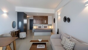 A modern living room with a sofa, coffee table, and a dining area. - Serenity Suite Caldera View with Hot Tub (Thira - Santorini)