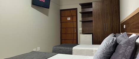 A hotel room with a bed, two bedside tables, a wardrobe, and a television displaying the Netflix logo.