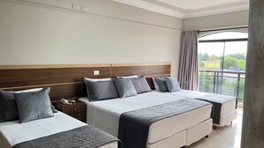A hotel room with two beds, a wooden headboard, a nightstand, and a view of greenery through the window. - Gutierrez Hotel (Americana)