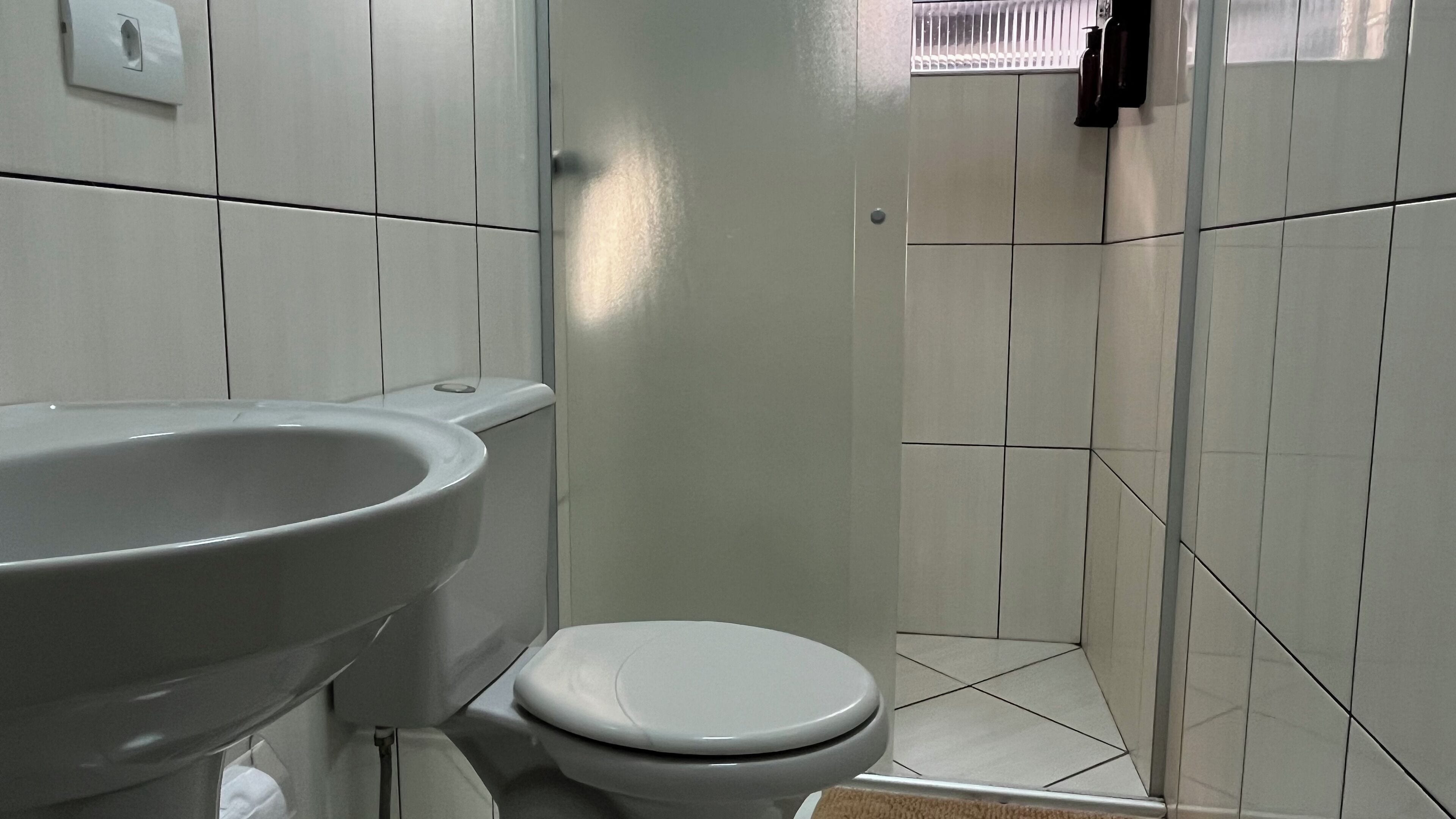 A bathroom with a white sink, toilet, and shower area.