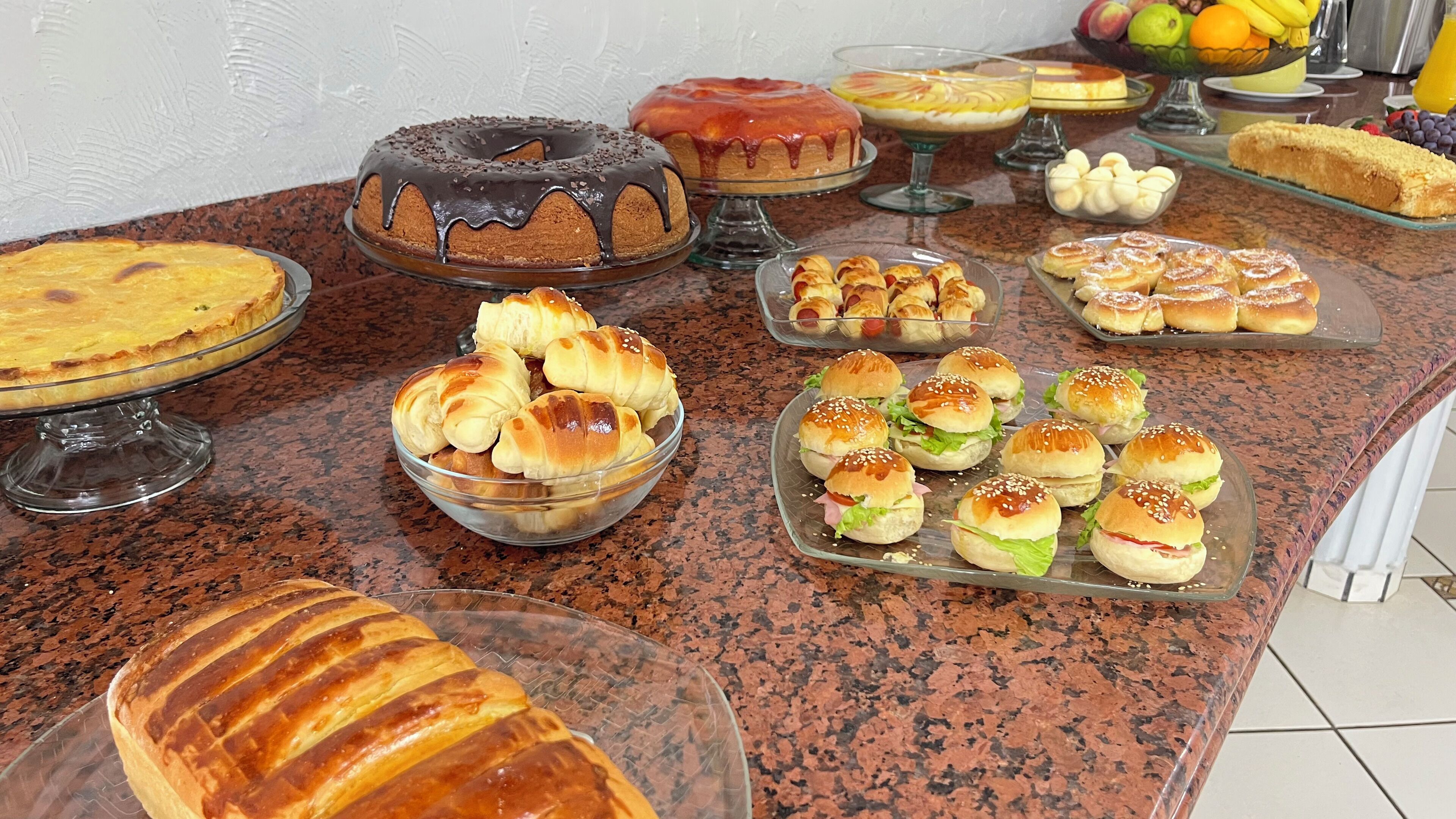A buffet table with various baked goods including cakes, pastries, and sandwiches.