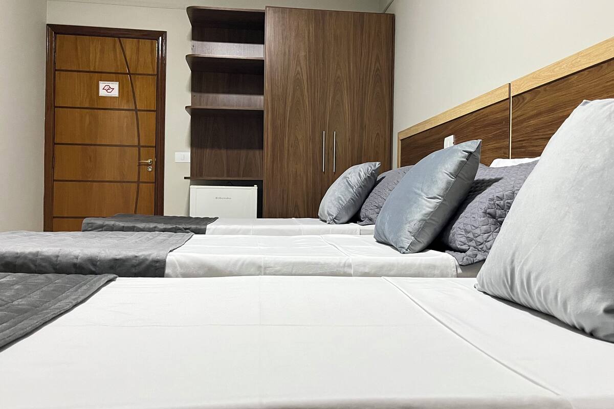 A hotel room with a bed, a wardrobe, and a chest of drawers.