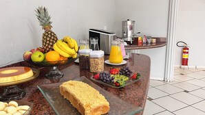 A breakfast buffet with fruits, cereals, and a coffee machine. - Gutierrez Hotel (Americana)