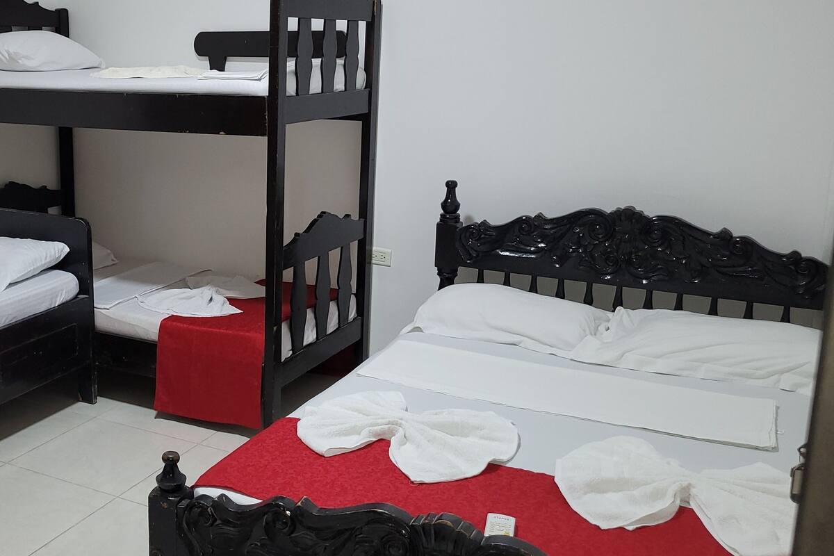 A room with two bunk beds, each with a red bedspread and white pillows.