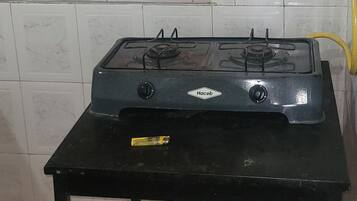 Una cocina con estufa a gas, refrigerador y una mesa de comedor.