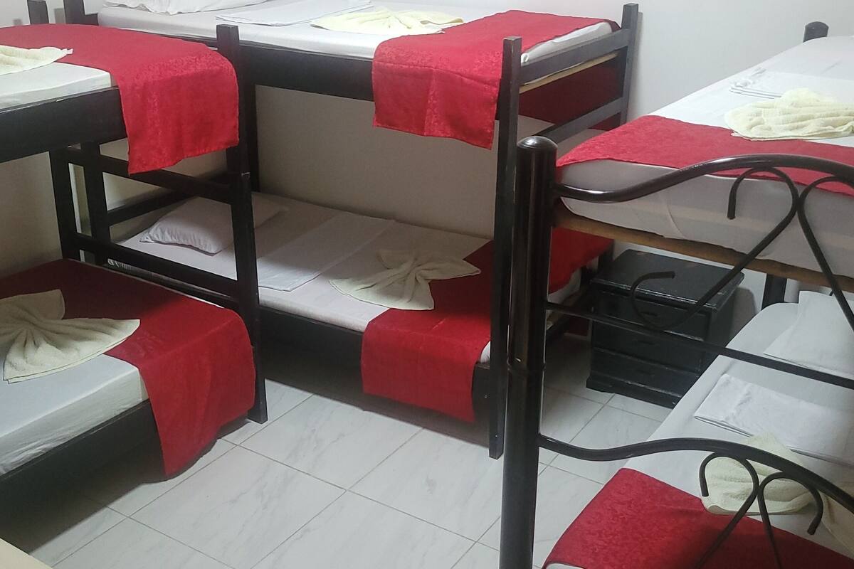 Bunk beds with red blankets, white sheets, and a black metal frame.