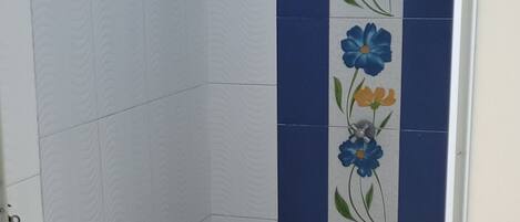 A bathroom with white walls, blue and white patterned tiles, and a floral design on the wall.