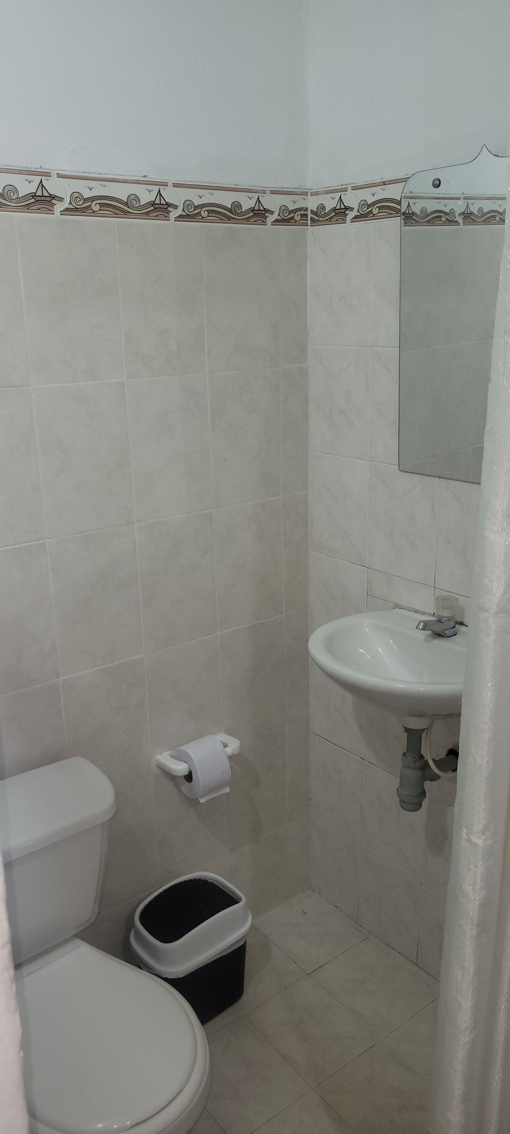 Une salle de bain équipée de toilettes, d’un lavabo et d’une poubelle.