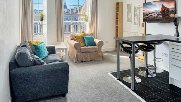 Ein modernes Wohnzimmer mit zwei Sofas, einem Esstisch und einem Fernseher.