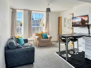 Een moderne woonkamer met twee banken, een eettafel en een televisie.