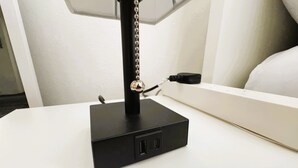 Ein schwarzes elektronisches Gerät mit Kette und Stecker auf einer weißen Oberfläche.
