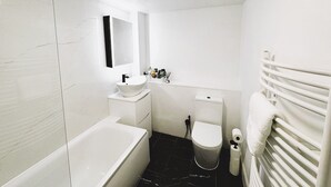Ein modernes Badezimmer mit Badewanne, Waschbecken, Toilette und Handtuchhalter.