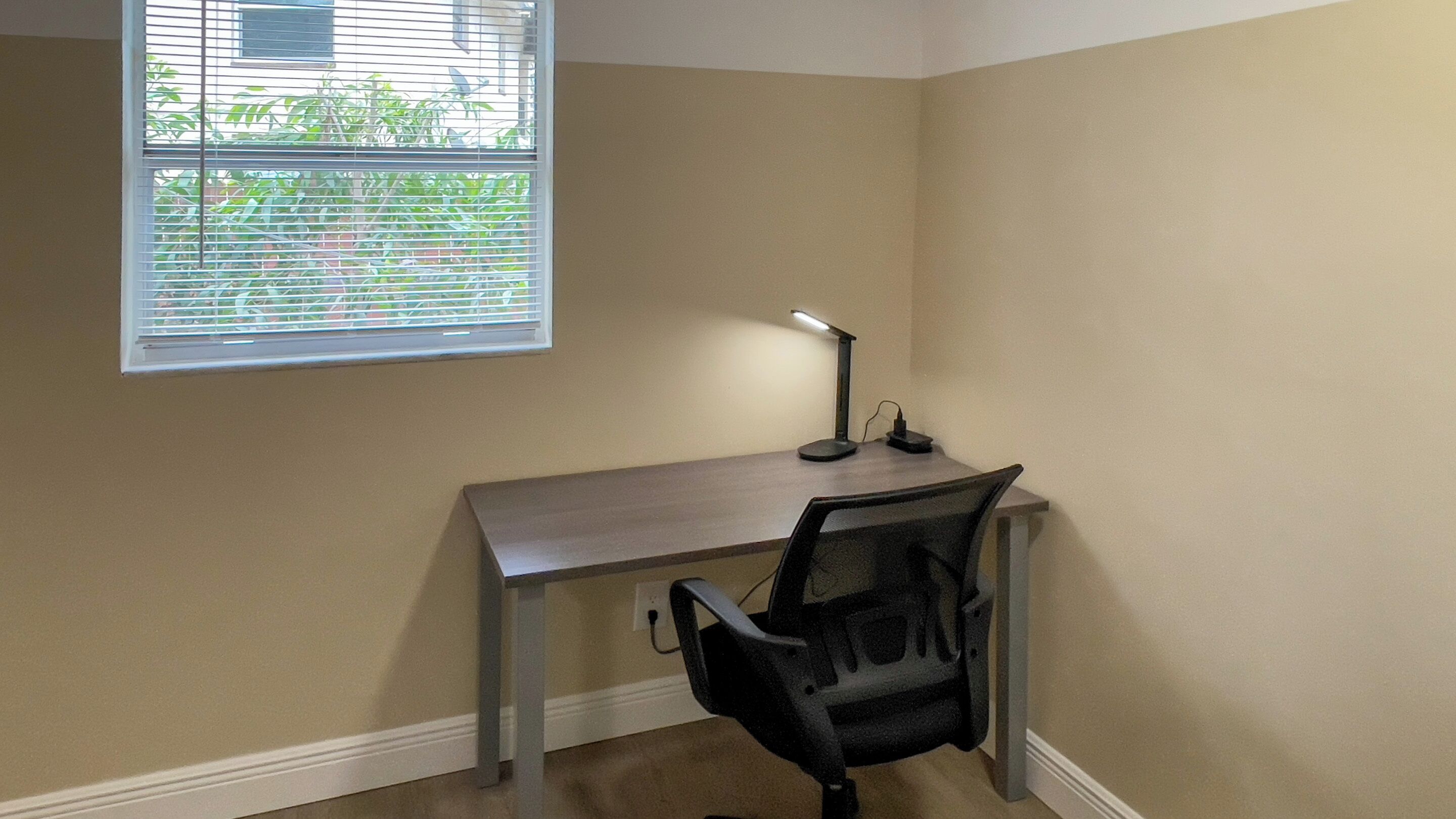 A small office space with a desk, chair, and a window with blinds.