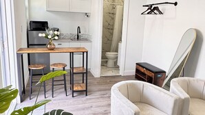 A modern living room with a sofa, a coffee table, and a potted plant. - Miami North Beach Guesthouse (North Miami Beach)