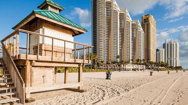 A beach with a lifeguard tower and tall residential buildings in the background. - Miami North Beach Guesthouse (North Miami Beach)