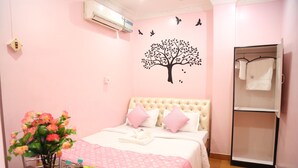 Une chambre à coucher comprenant un lit, une commode, une coiffeuse et un climatiseur fixé au mur.