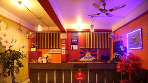 Un espace d’accueil comprenant un comptoir de réception, un ventilateur de plafond et un panneau indiquant la réception.