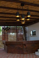 A wooden ceiling with hanging pendant lights, a brick floor, and a wooden counter with a small window.
