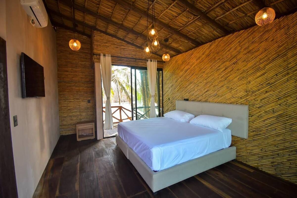 Un dormitorio con una cama grande, un televisor montado en la pared y un techo con textura tejida.