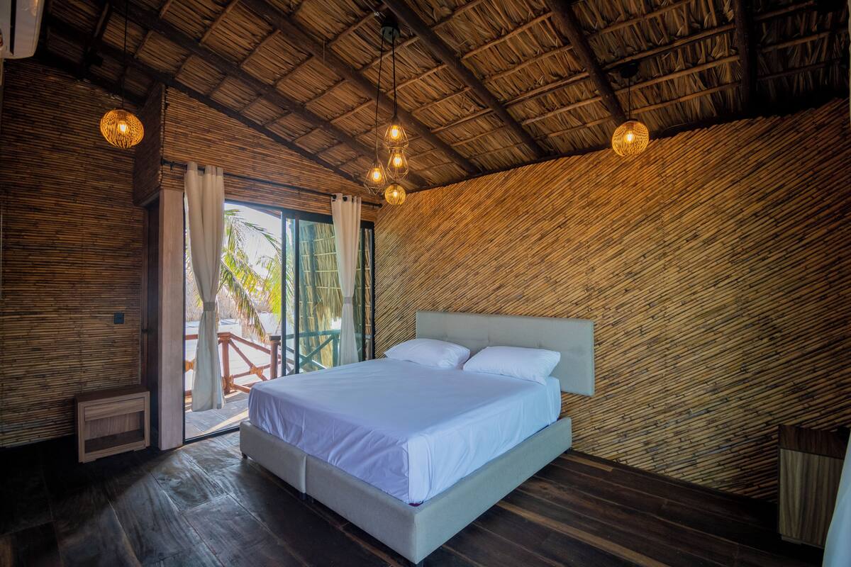 Un dormitorio con una cama grande, paredes de madera y un techo de paja.