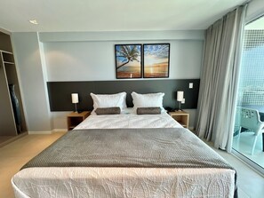 A hotel room with a large bed, two bedside tables, a nightstand, a headboard, and a window with curtains. - RN STUDIO - APTO 905 (Maceió)
