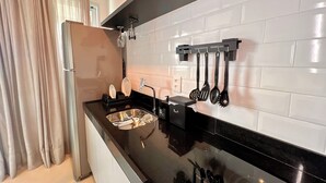 A modern kitchen with a black countertop, stainless steel sink, and a hanging utensil rack. - RN STUDIO - APTO 905 (Maceió)