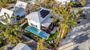 A modern house with a swimming pool, surrounded by palm trees and solar panels. - Playa Palma Private Pool Home 4 Minute Walk to Holmes Beach on AMI (Holmes Beach)