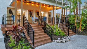 A modern house with a covered porch, wooden steps, and a black railing. - Playa Palma Private Pool Home 4 Minute Walk to Holmes Beach on AMI (Holmes Beach)