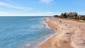 A wide sandy beach with gentle waves, a clear sky, and sparse vegetation. - Playa Palma Private Pool Home 4 Minute Walk to Holmes Beach on AMI (Holmes Beach)
