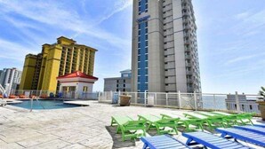 A rooftop pool area with lounge chairs and a view of high-rise buildings. - Oceanfront Oasis: Your Ideal 1BR Condo Escape (Myrtle Beach)