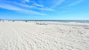 A wide sandy beach with footprints and a few people scattered across it. - Oceanfront Oasis: Your Ideal 1BR Condo Escape (Myrtle Beach)