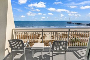 Un balcon avec vue sur la plage et l’océan, comprenant deux chaises et une petite table.