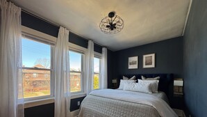 A bedroom with a large bed, two bedside lamps, and a ceiling fan. - THE MILL HOUSE - Charming Historic Cottage 1.5 miles from the US Open (Oakmont)
