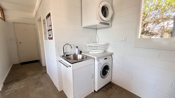 Une buanderie équipée d’un lave-linge, d’un évier et d’un sèche-linge.