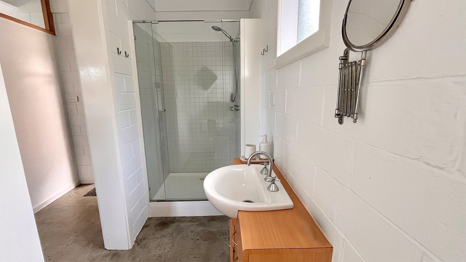 A bathroom with a glass-enclosed shower, a white sink, and a wooden cabinet.