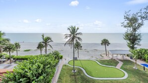 Blick auf einen Strand mit Palmen, einen Golfplatz und einen klaren Himmel.