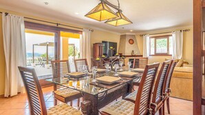 A dining area with a glass table, wooden chairs, and a chandelier. - New! Villa Beni - Santa Eulalia (Ibiza)