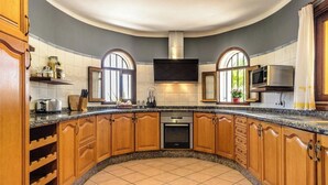 A kitchen with wooden cabinets, a built-in oven, and a large window. - New! Villa Beni - Santa Eulalia (Ibiza)